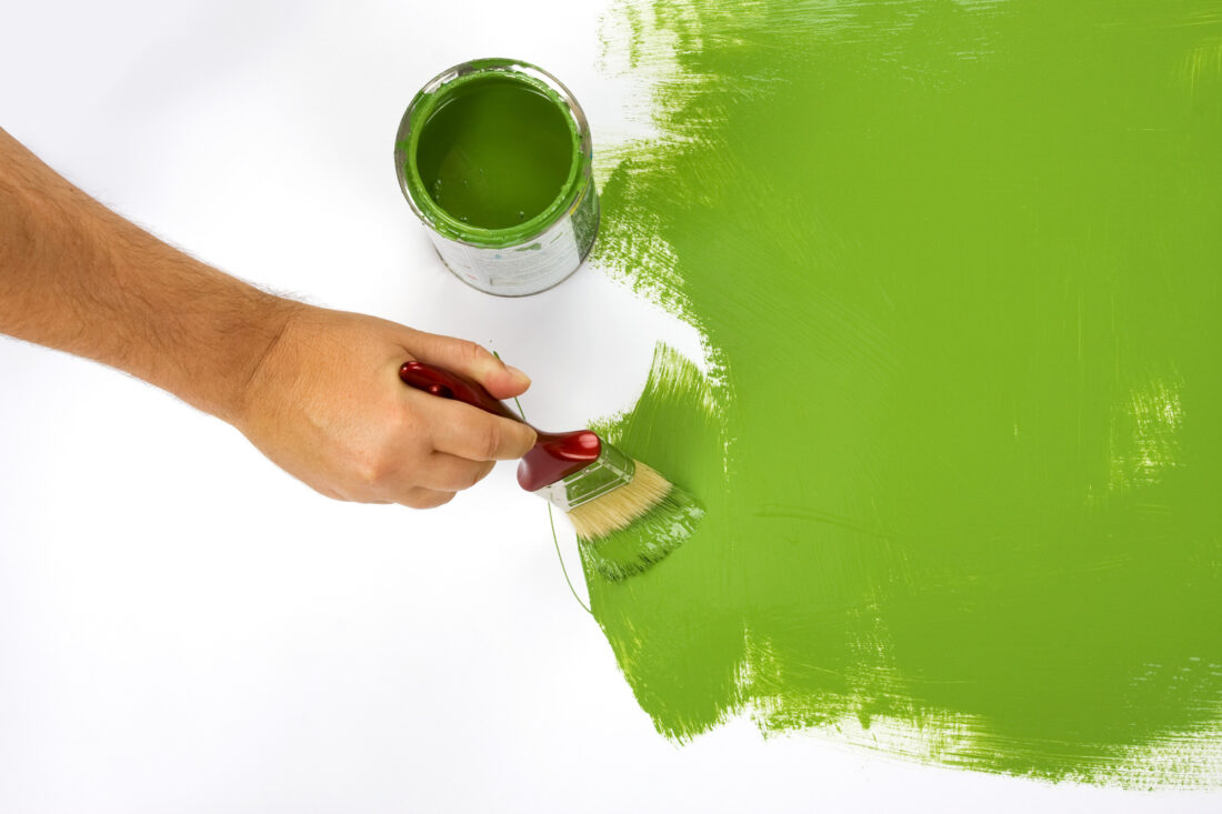 Hand painting white surface with green paint
